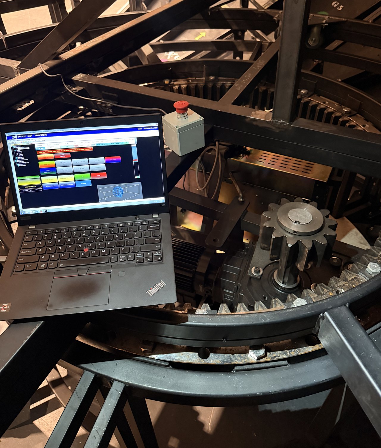 Ring-gear drive beside an emergency stop and control laptop.