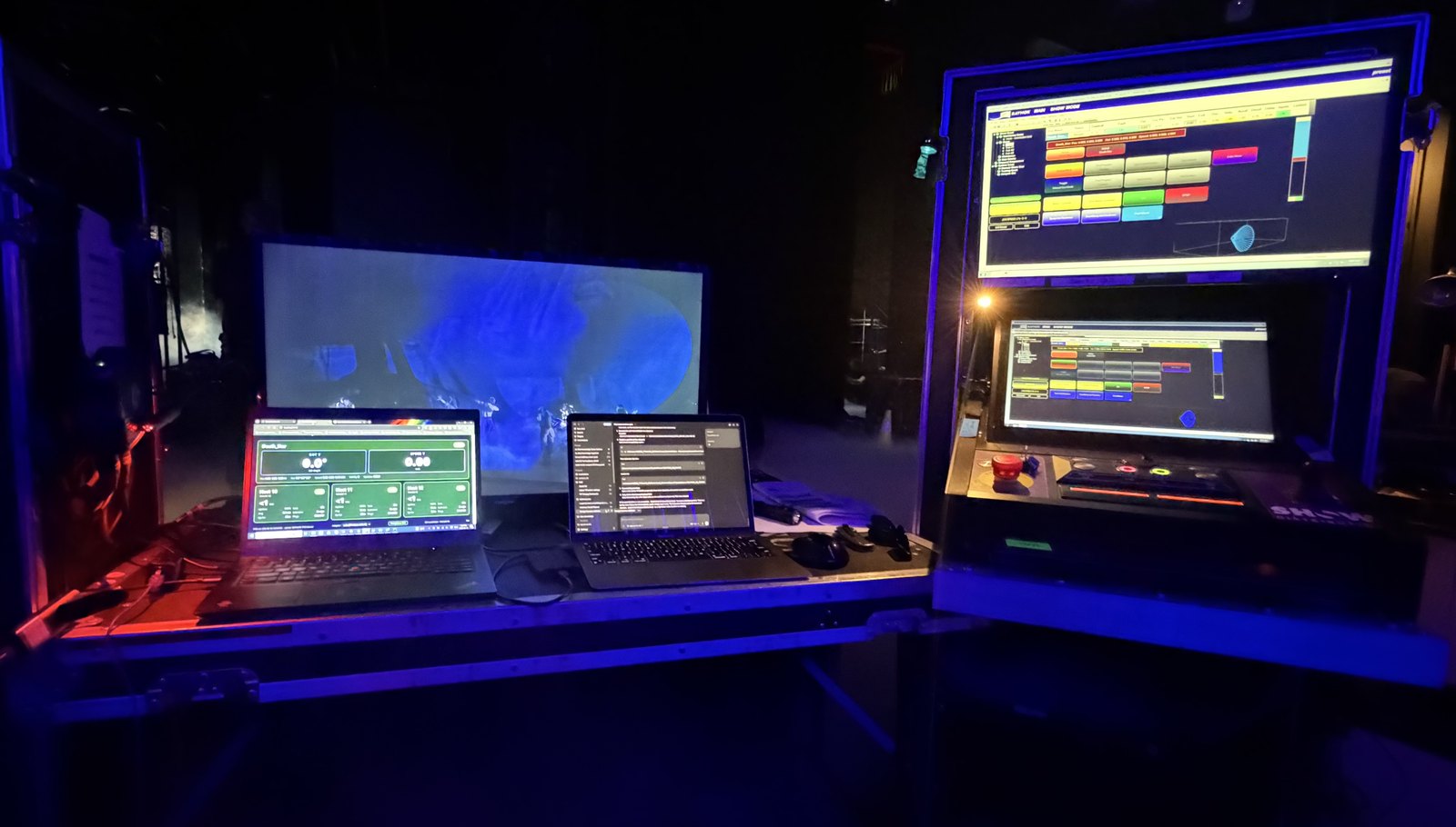 Two laptops beside a rack of control screens at side stage.