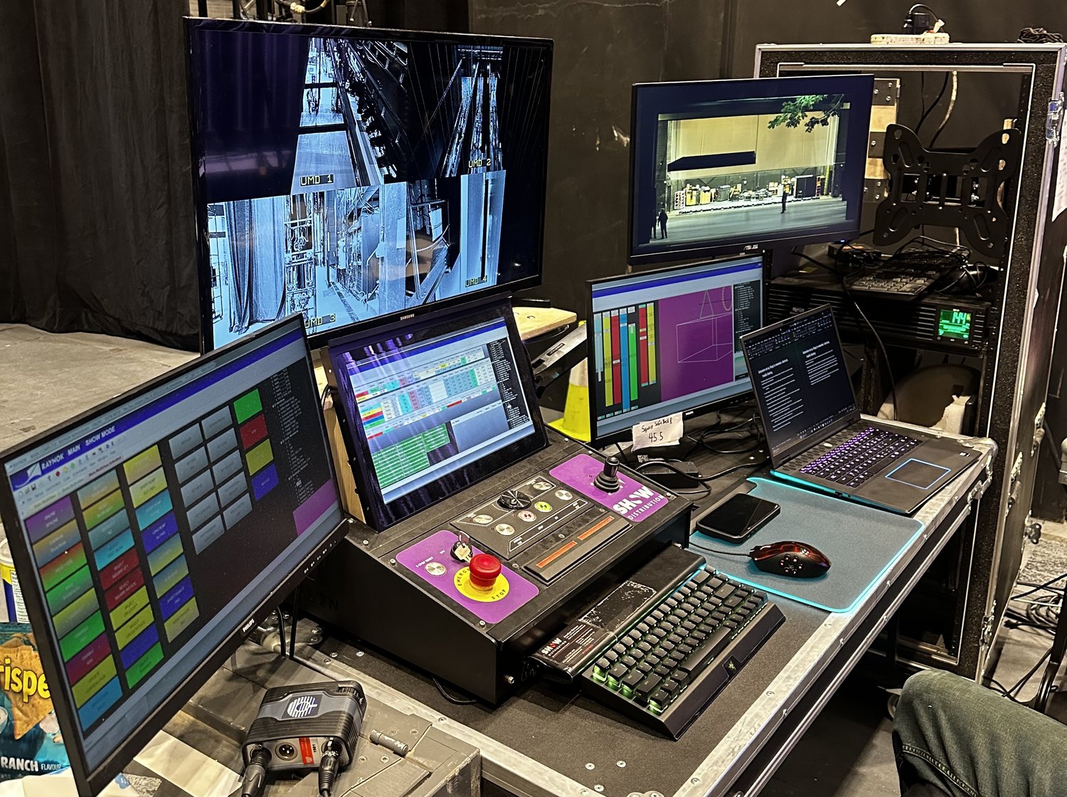 Side-stage operator console with control screens, camera views and a laptop.